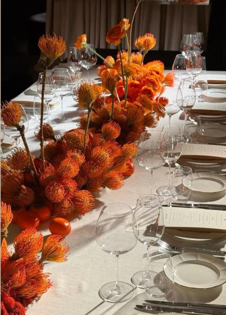 Mesa posta com arranjos de flores laranja